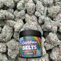 Jar of 'Rainbow Belts' candy on a background of green flower